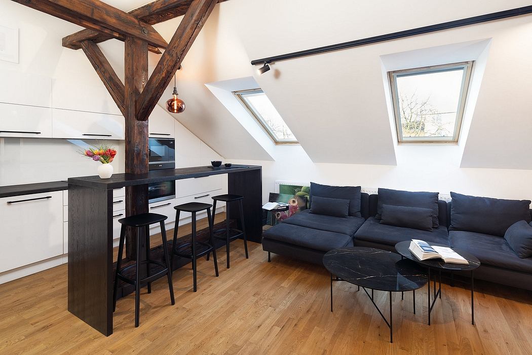Open-plan attic living space with exposed wooden beams, modern kitchen, and large sofa.
