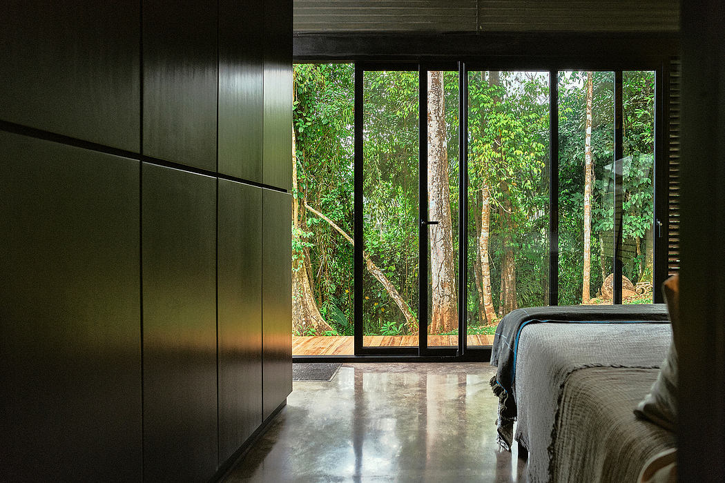 A modern, minimalist bedroom with large windows overlooking a lush, forested landscape.