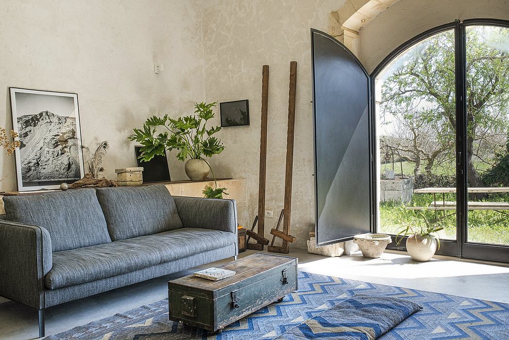 Spacious living room with rustic furniture, large arched window, and natural decor elements.