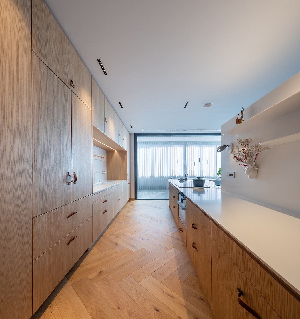 Sleek modern kitchen with wood cabinets, herringbone floor, and large sliding window.