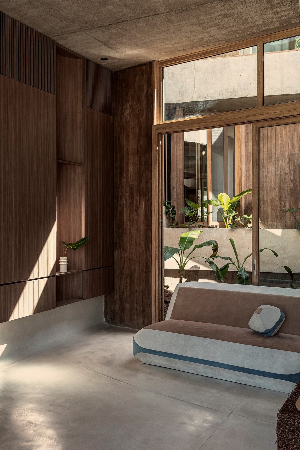 A rustic yet modern interior space with wooden walls, large windows, and a concrete seating area.