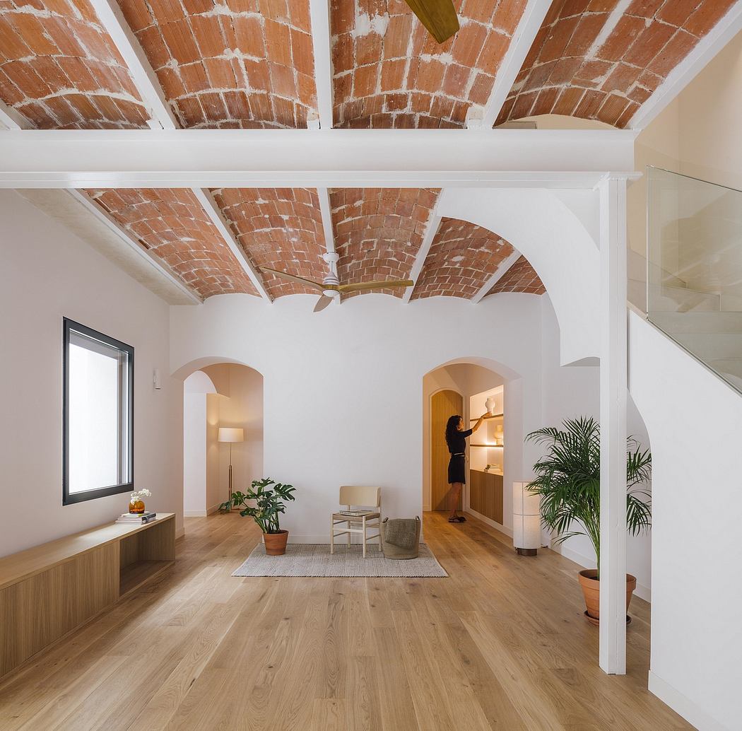 A minimalist living room with a stunning arched brick ceiling and hardwood flooring.