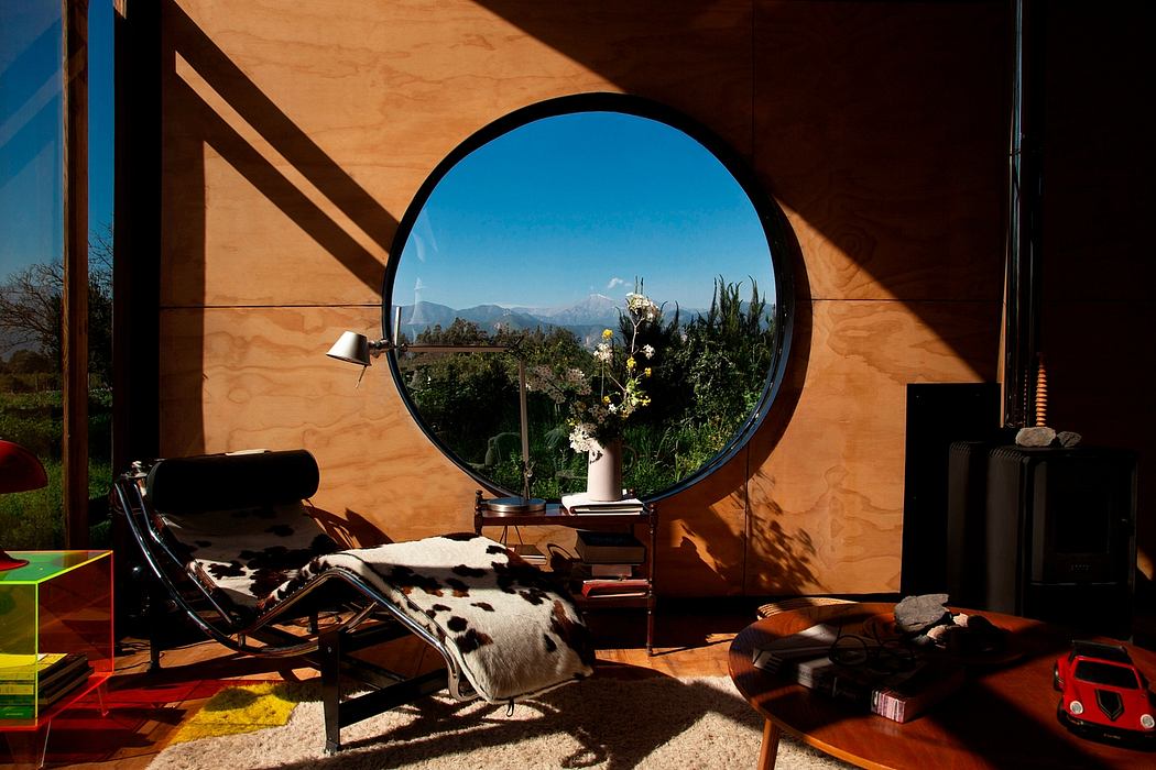A cozy and rustic interior with a large circular window framing a scenic outdoor view.