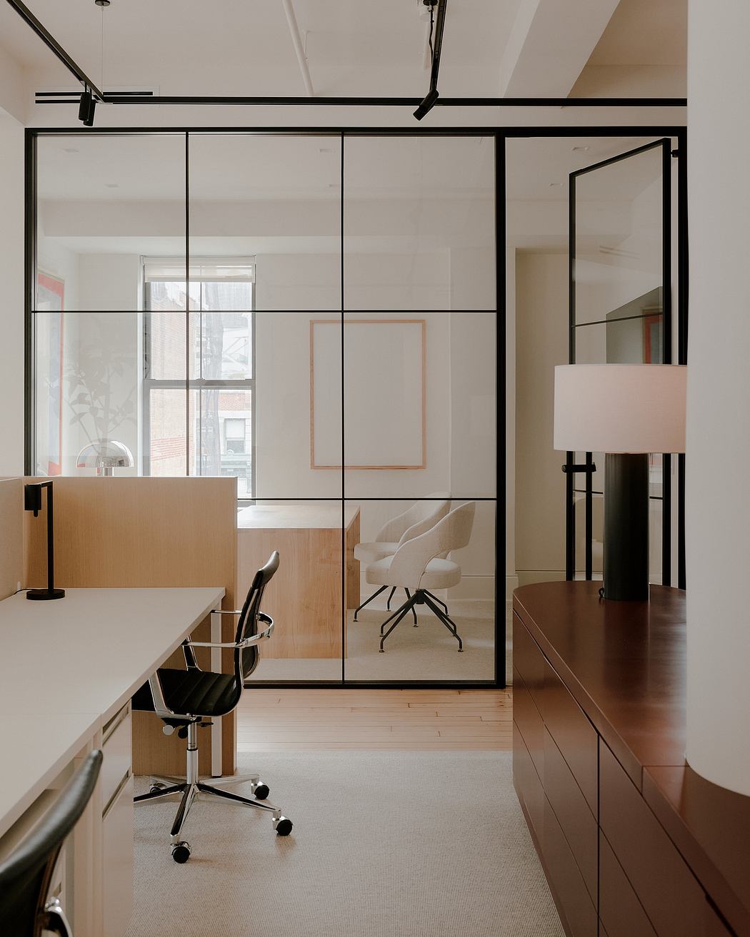 Sleek, modern office with minimalist glass partitions, wood furniture, and ergonomic chair.