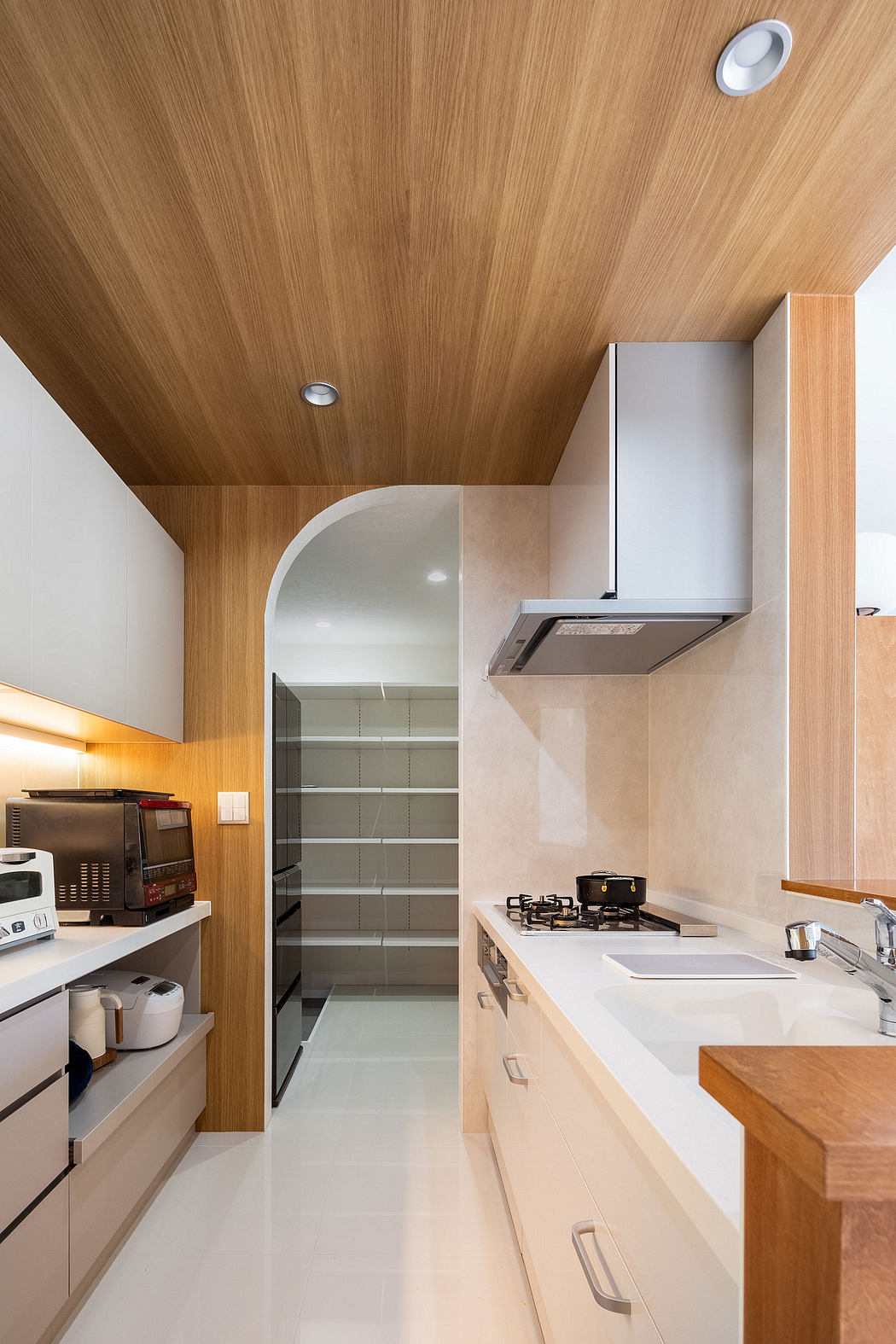 Sleek, minimalist kitchen design with wood paneled ceiling, built-in shelves, and modern appliances.