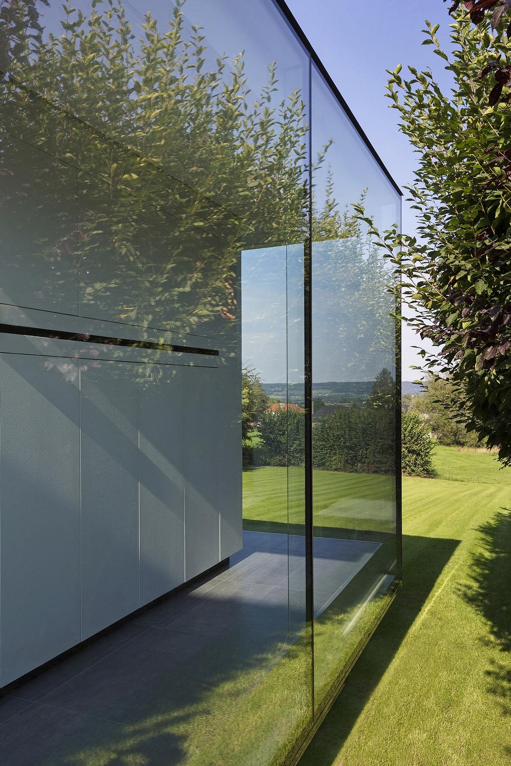 Expansive glass walls framing a lush outdoor landscape, showcasing modern architectural elements.