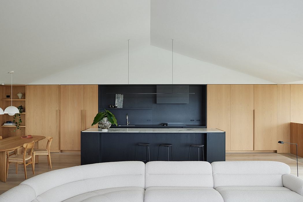Sleek, minimalist kitchen with black cabinetry, wooden accents, and a modern dining area.
