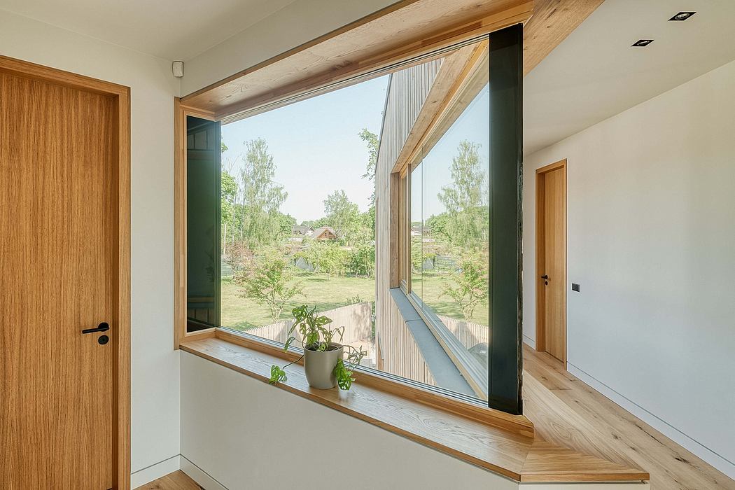 Window with wooden frame overlooking lush green garden, minimalist interior design.
