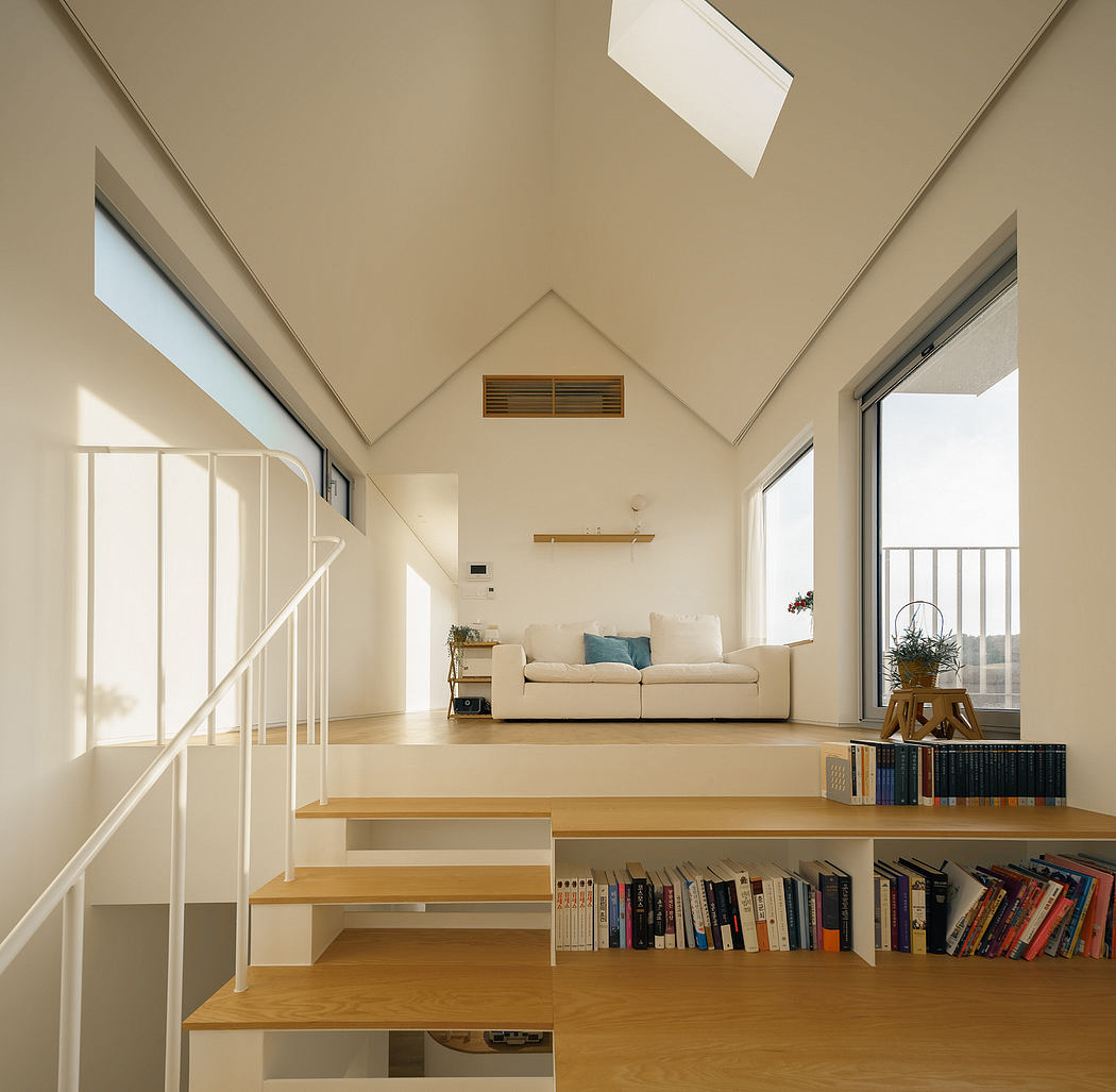 Bright, airy interior with vaulted ceiling, stairs, bookshelves, and cozy seating area.