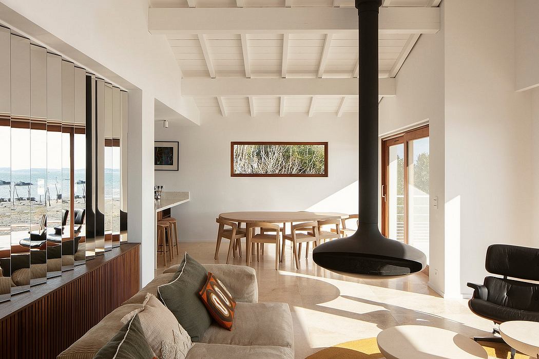 Bright, open-plan living space with exposed wooden ceiling beams and a central fireplace.