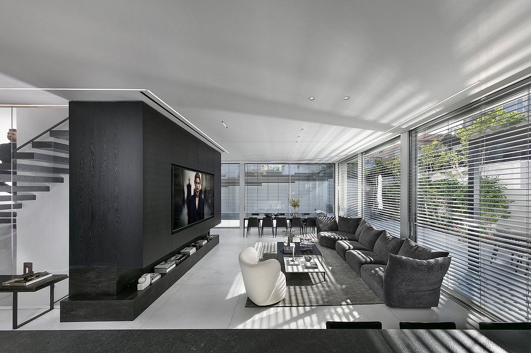 Spacious modern living room with sleek furniture, large windows, and black entertainment unit.