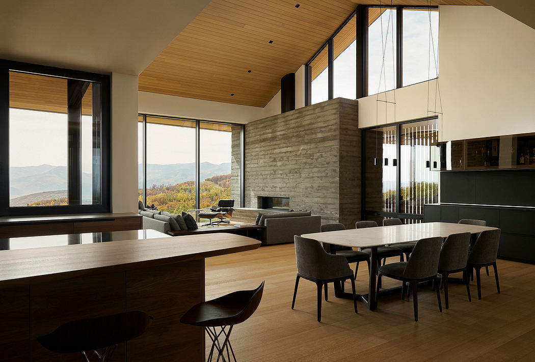 Open concept living room with vaulted wood ceiling, concrete fireplace, and panoramic mountain views.