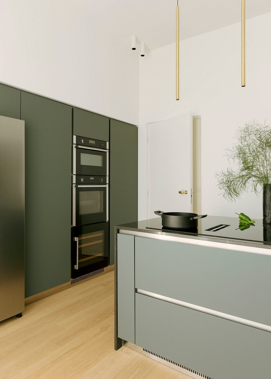 Contemporary kitchen with sleek, minimalist green cabinets, integrated appliances, and modern lighting.