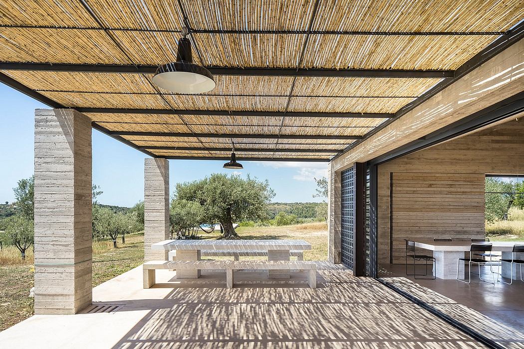 Rustic outdoor patio with bamboo-covered roof, wooden furniture, and scenic countryside view.