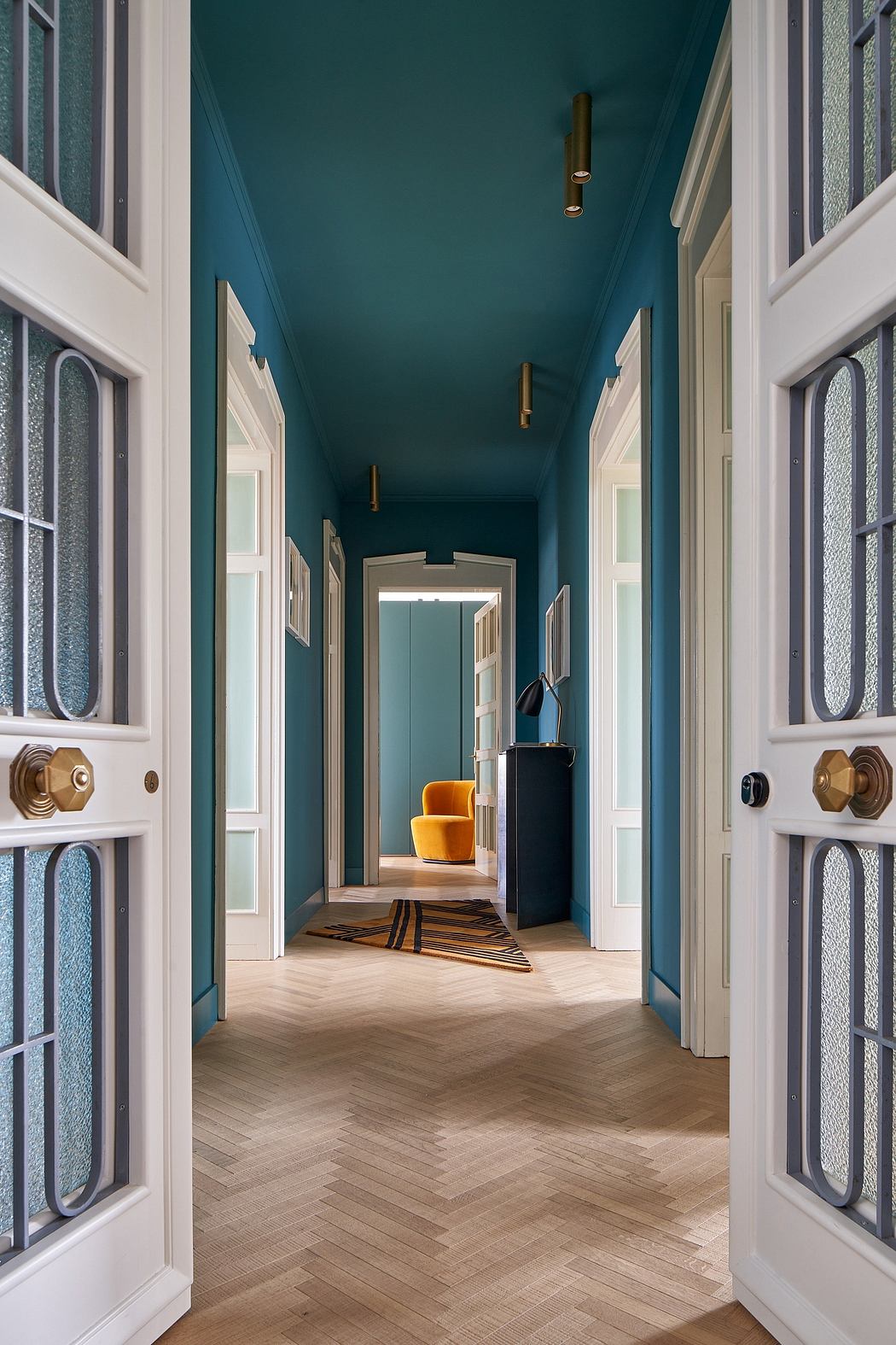 A vibrant, richly-decorated hallway with ornate doors, a striking teal ceiling, and stylish furnishings.