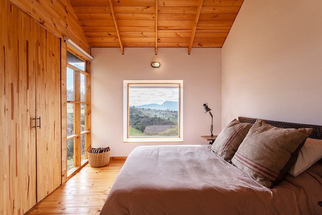 Cozy cabin bedroom with wood-paneled walls, beamed ceiling, and a scenic window view.