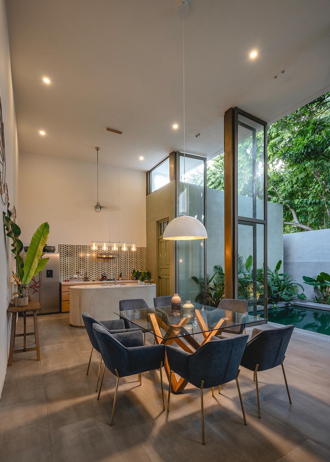 Spacious, open-concept living area with modern furniture, glass walls, and lush greenery.