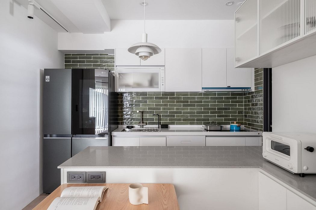 Modern kitchen with sleek gray cabinetry, black appliances, and a tiled backsplash.