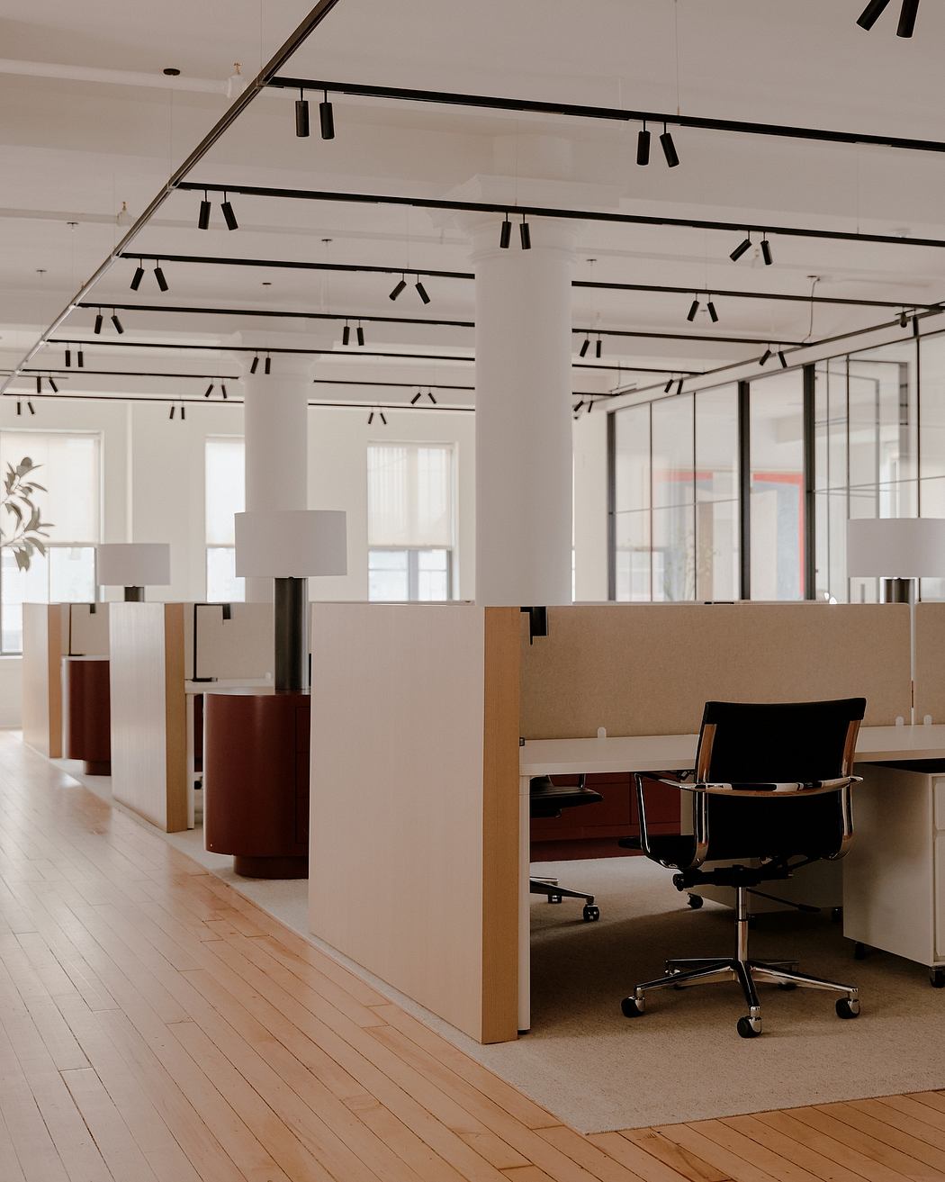 Contemporary open-plan office space with sleek modular workstations, recessed track lighting, and wood flooring.
