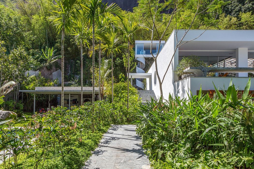A tropical garden surrounds an elegant modern villa with an open-concept design.