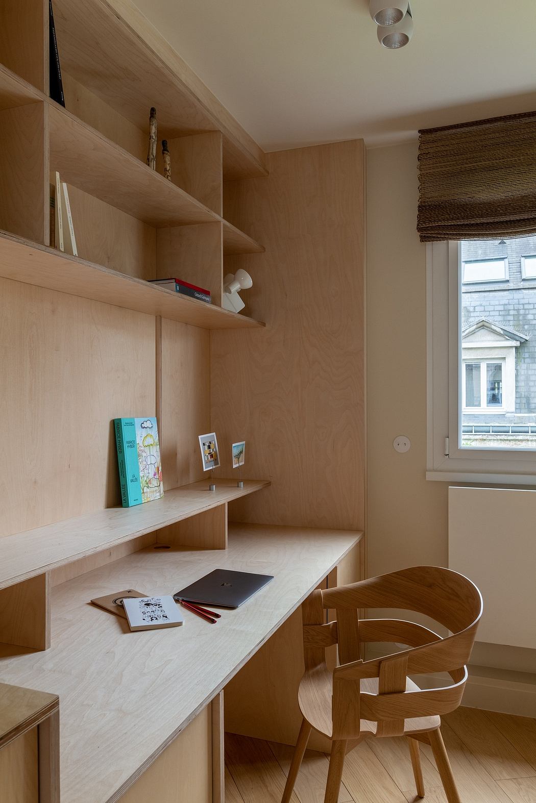 Cozy home office with built-in wooden shelves, desk, and chair - a functional and minimal design.