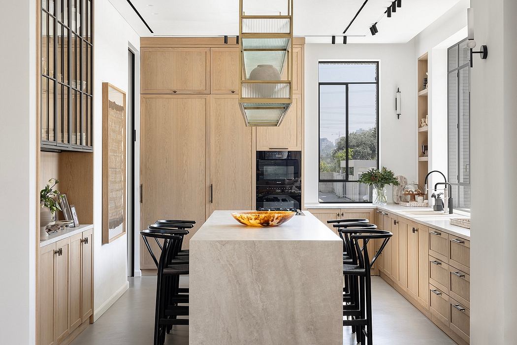 An airy, modern kitchen with a large stone island, natural wood cabinetry, and sleek black accents.