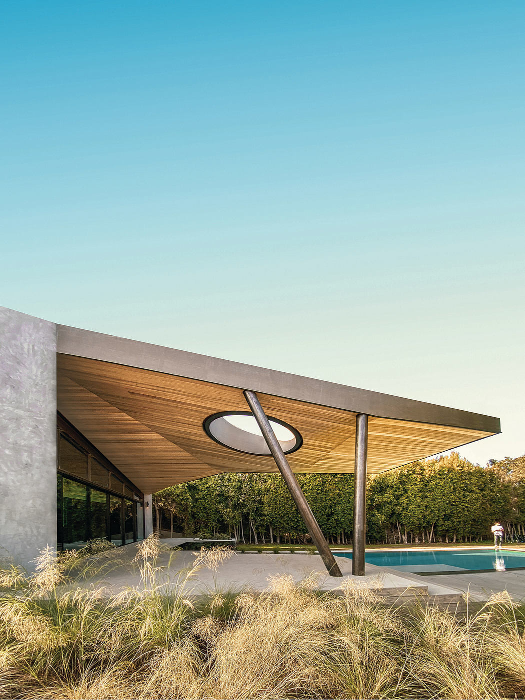 Striking contemporary structure with wood-paneled roof and sculptural supports near a pool.