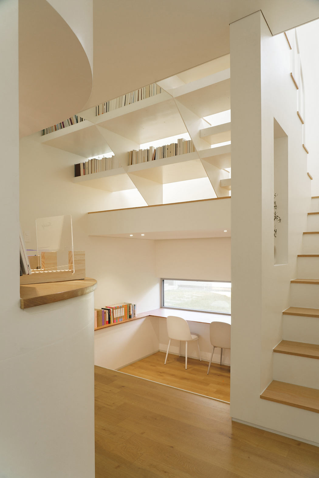 Airy, minimalist interior with shelving, seating nook, and wooden flooring highlighting architectural design.