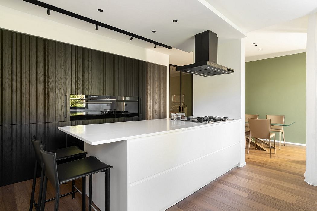 Modern kitchen with clean-lined, minimalist design featuring a sleek white island and black cabinetry.