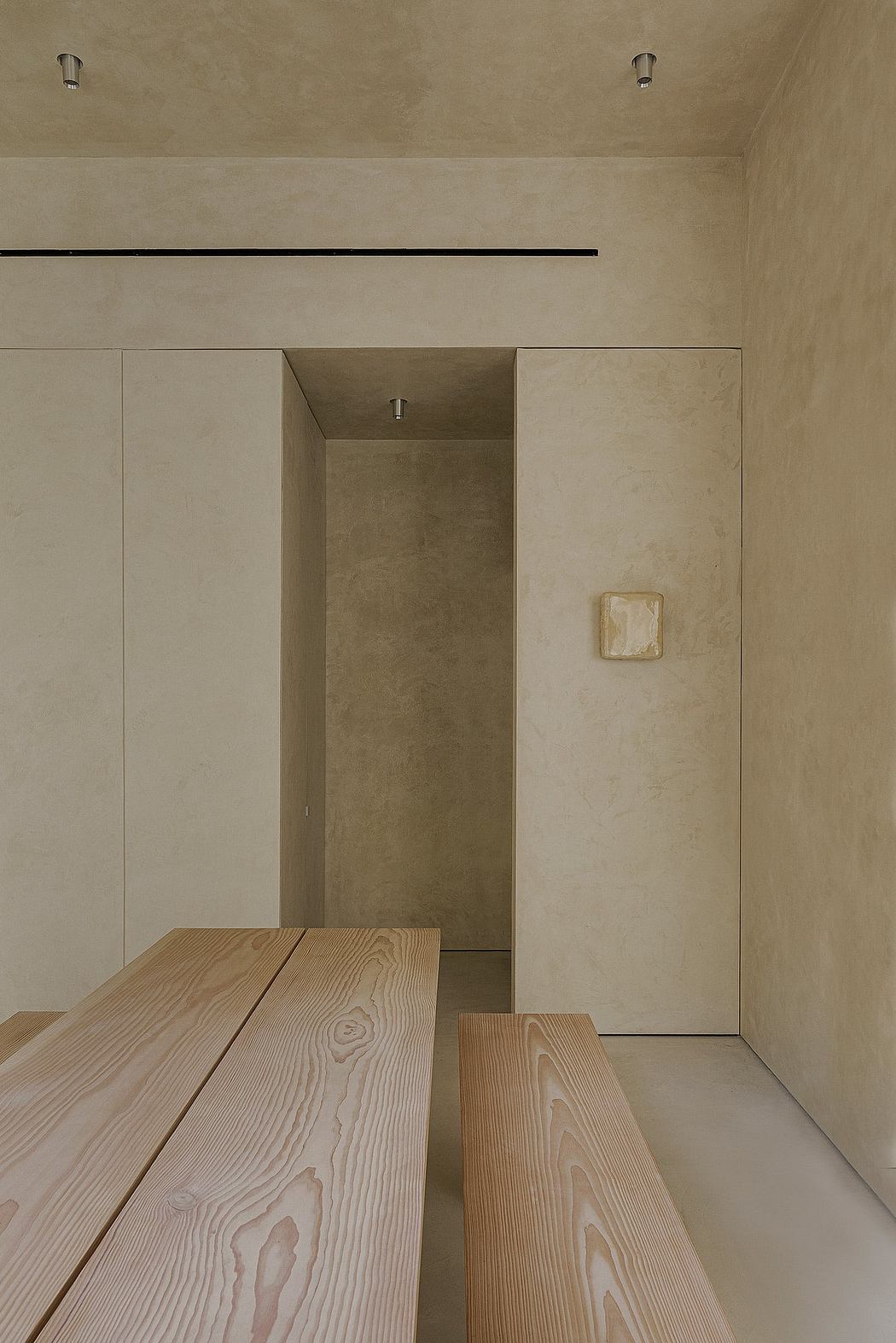 A minimalist entryway with wooden benches and a subtle recessed lighting fixture.