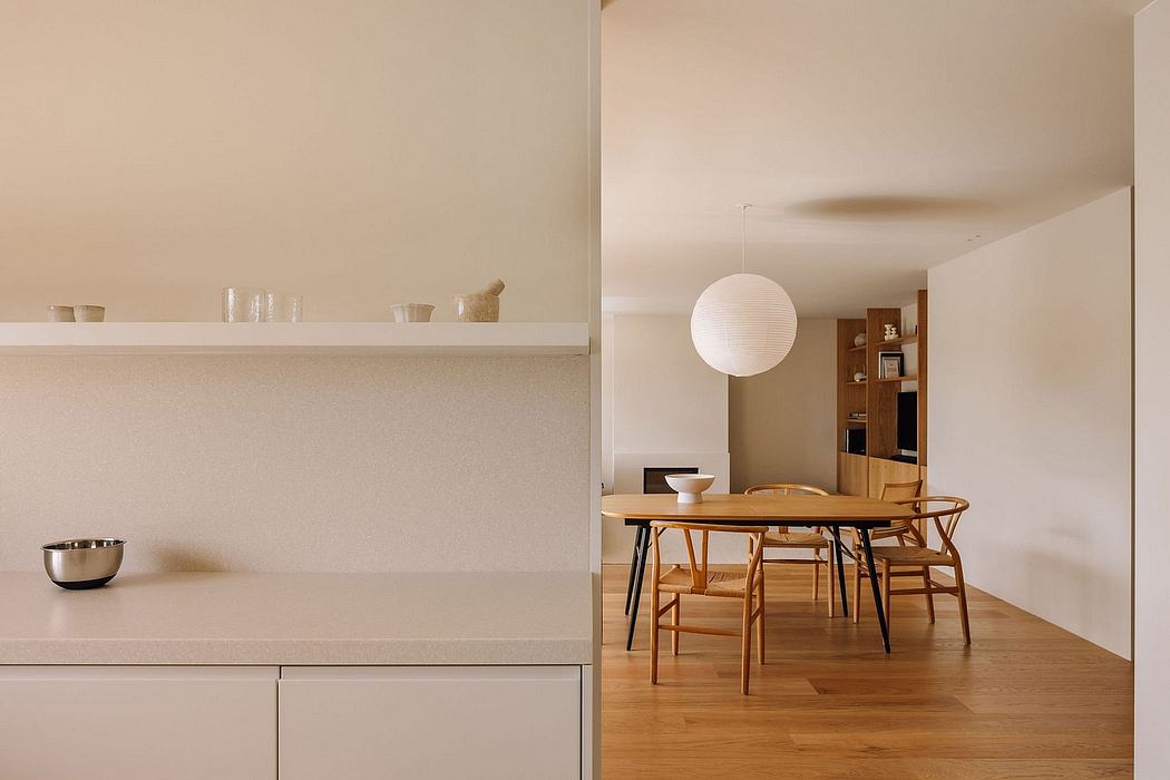 Minimalist dining area with wooden table, chairs, and globe light fixture.
