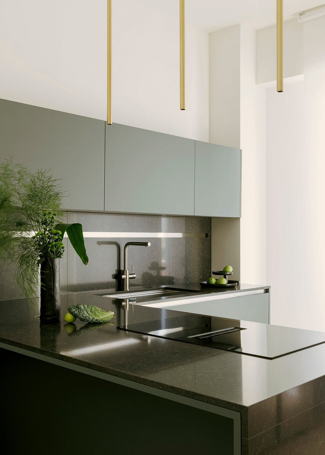 Minimalist kitchen with sleek gray cabinets, stainless steel sink, and green accents.