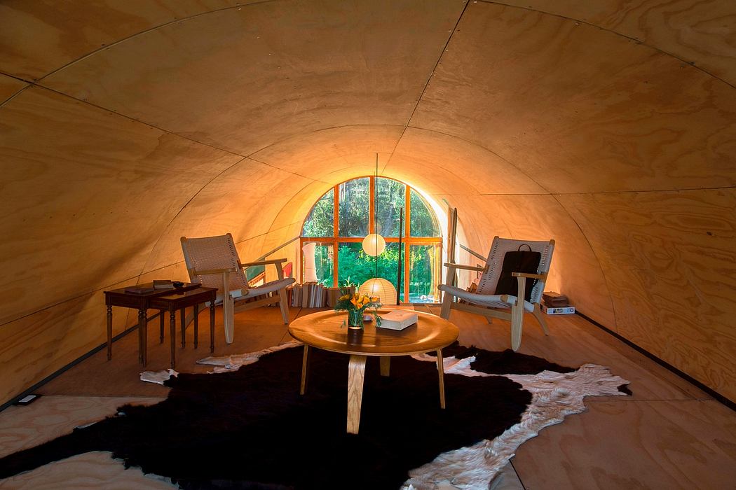 Cozy dome-shaped interior with arched windows, wooden furniture, and a plush area rug.