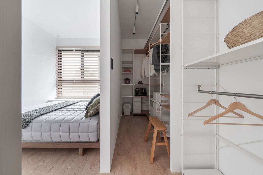 Minimalist bedroom with wooden furnishings, open closet storage, and natural lighting.