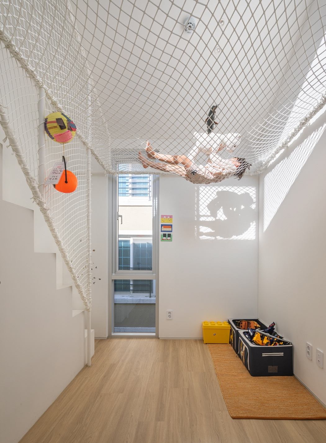 Modern interior with net ceiling, storage boxes, and hardwood flooring.