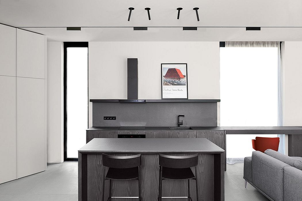 Minimalist kitchen design with sleek black and gray palette, geometric lighting, and framed artwork.