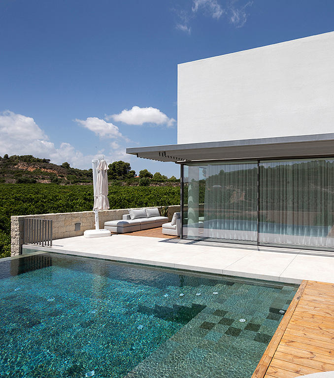 Sleek, modern architecture with a large glass window, pool, and outdoor seating area.
