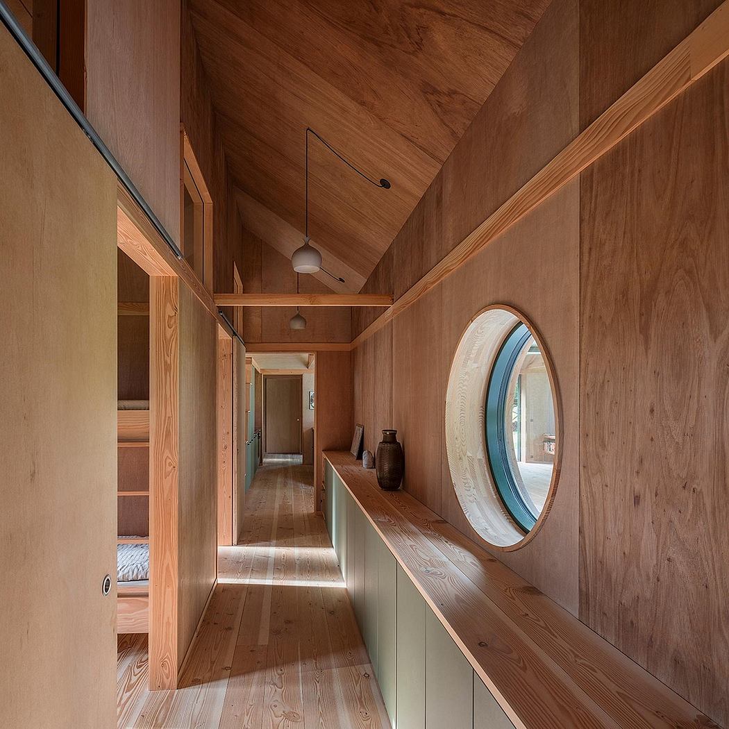 Warm-toned wooden hallway with circular mirror, built-in shelves, and pendant lighting.