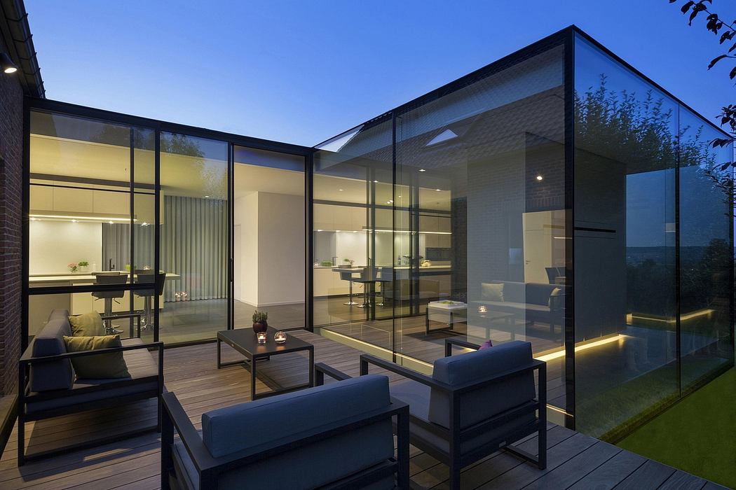 A modern, minimalist house with floor-to-ceiling glass walls, a spacious deck, and a cozy, well-lit interior.