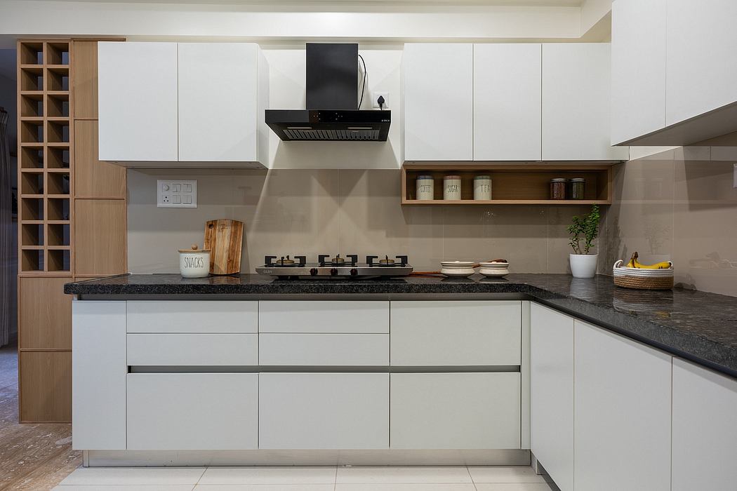 A modern, minimalist kitchen with sleek white cabinetry, dark granite countertops, and open shelving.