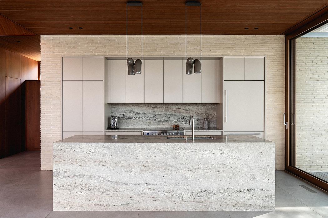 Sleek modern kitchen with white stone countertops, wood paneled walls, and minimalist cabinetry.