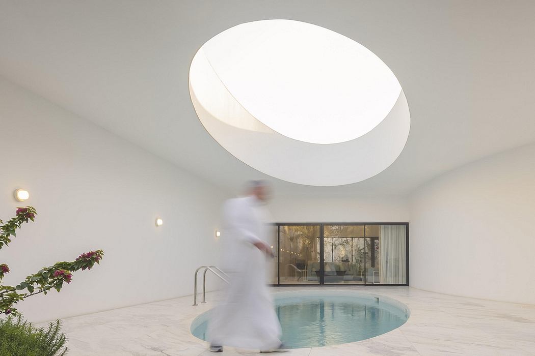 A modern indoor pool with a large, circular skylight illuminating the minimalist space.