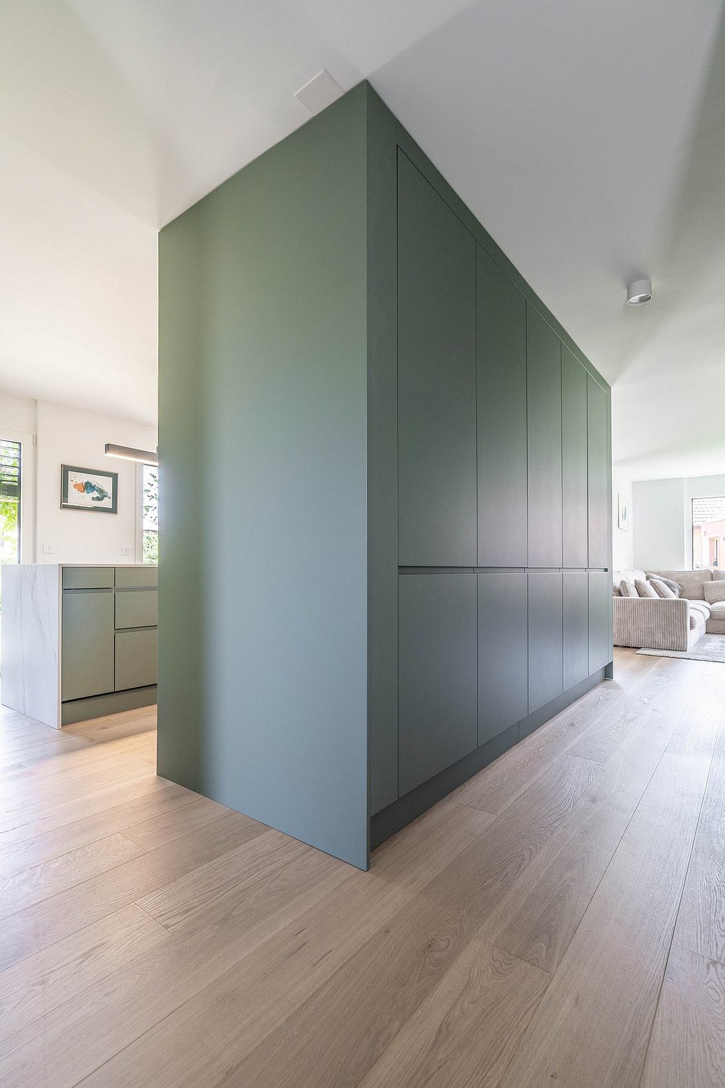 Sleek, minimalist cabinetry with a striking green-gray palette anchors the open-concept space.