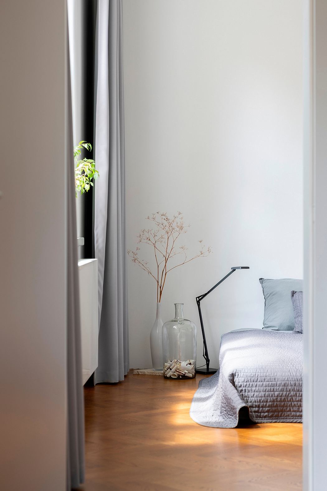 A cozy bedroom with minimalist decor, a large window, and a modern lamp.