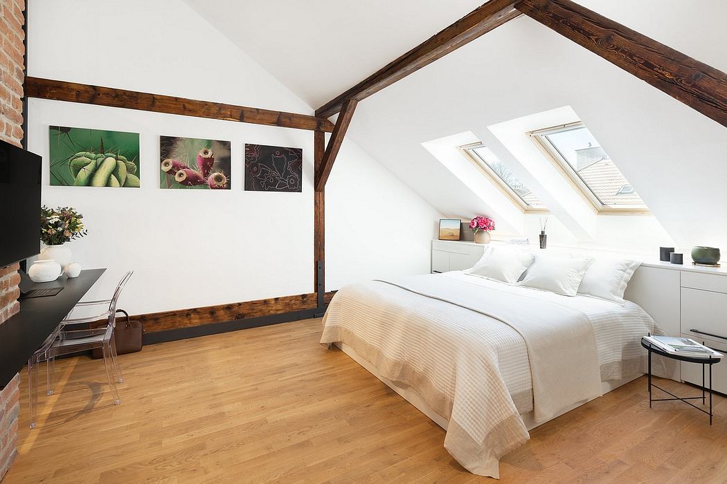 Cozy attic bedroom with exposed wooden beams, skylights, and minimal decor.