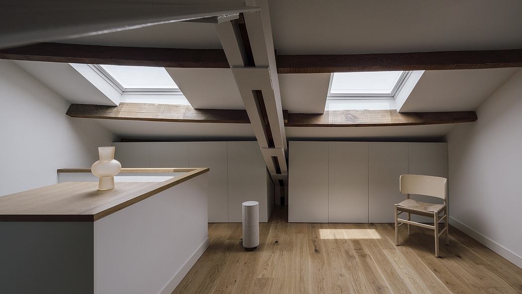 Contemporary attic space with exposed wooden beams, skylights, and minimal furniture.