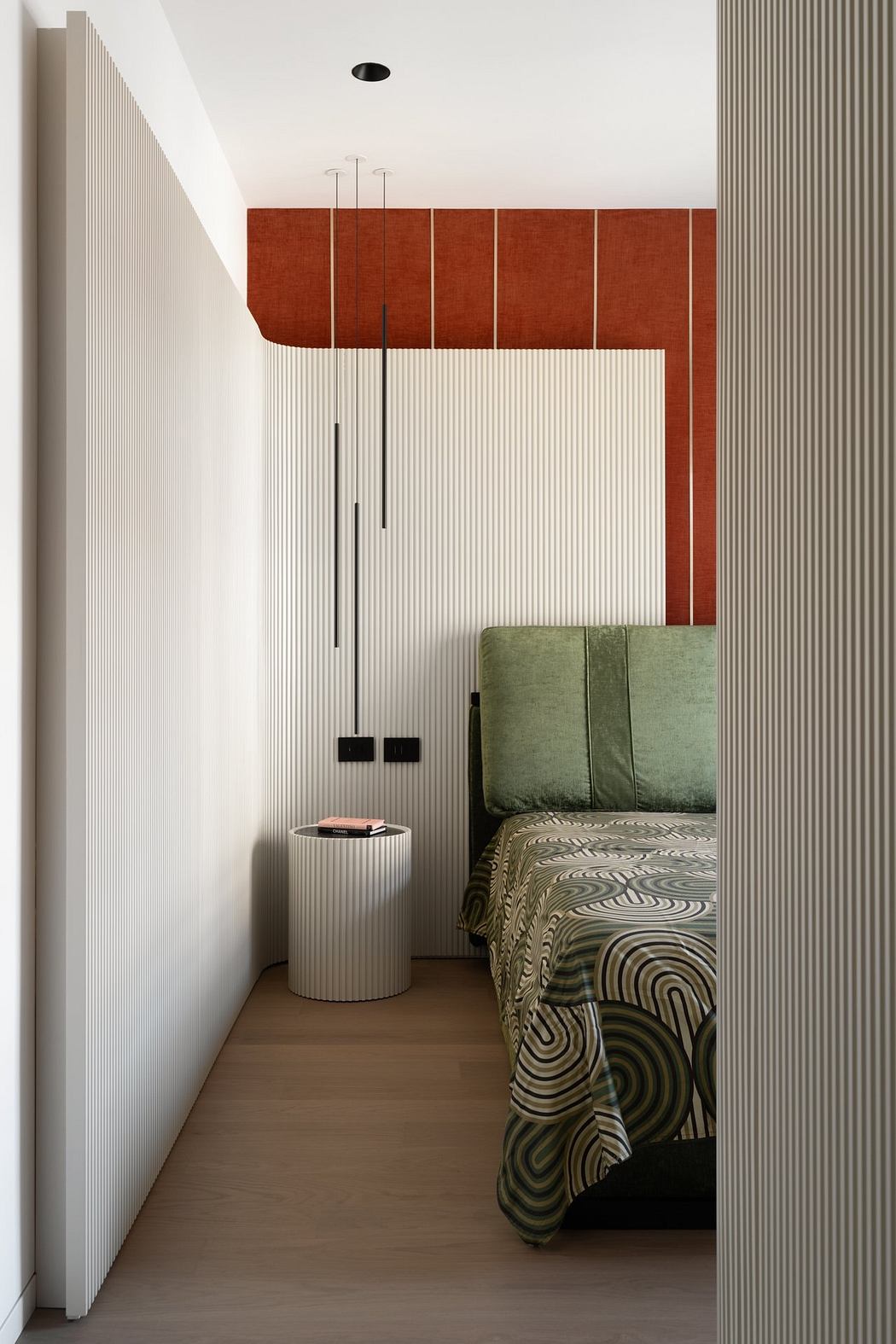 Minimalist bedroom with striped walls, patterned bedding, and a white side table.