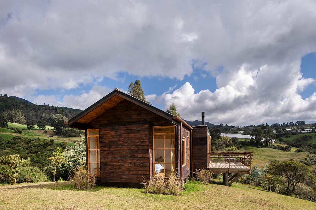 A rustic wooden cabin nestled in a lush, verdant landscape with a balcony and mountain views.