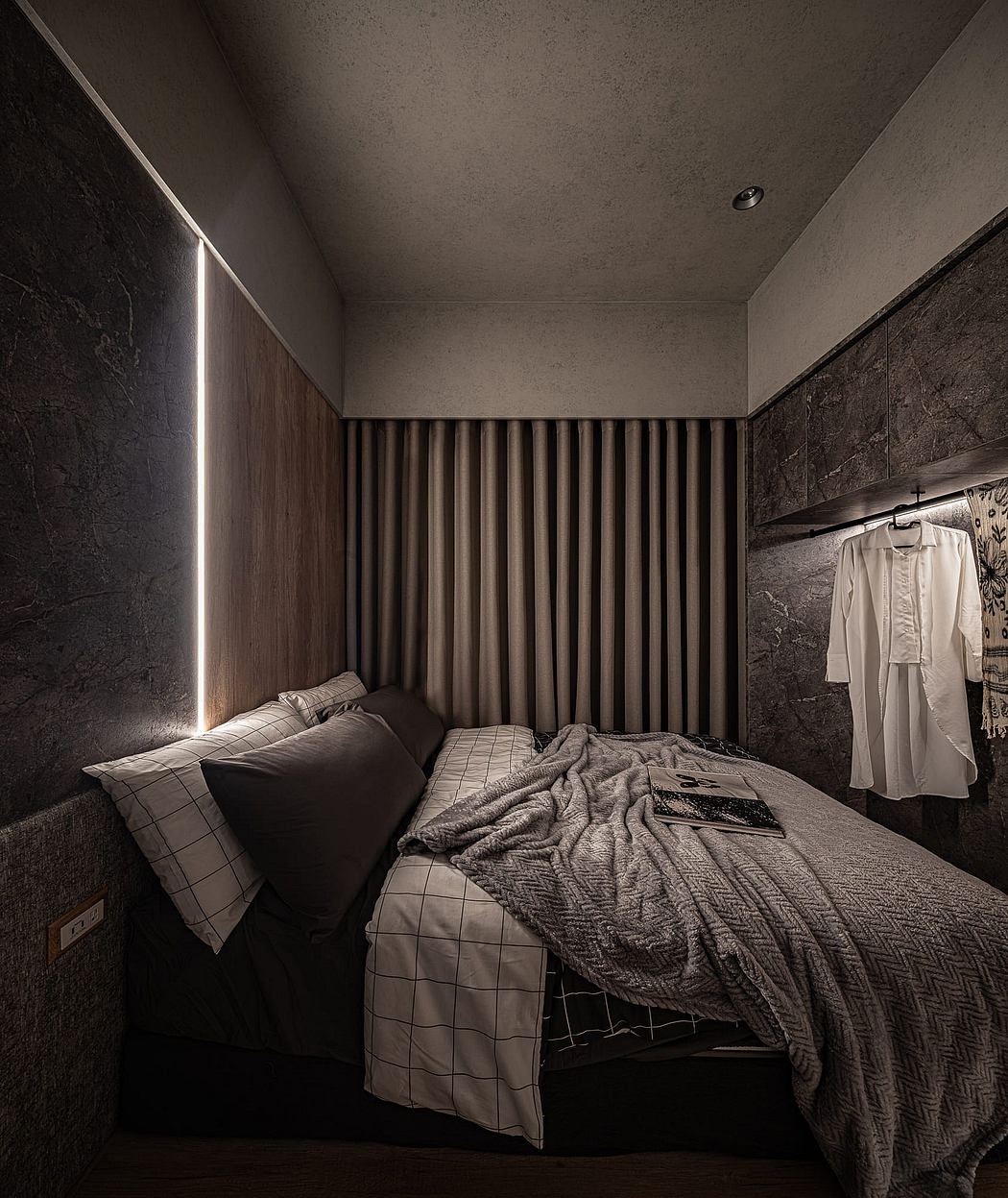 A monochrome bedroom with sleek furniture, textured walls, and dramatic lighting.