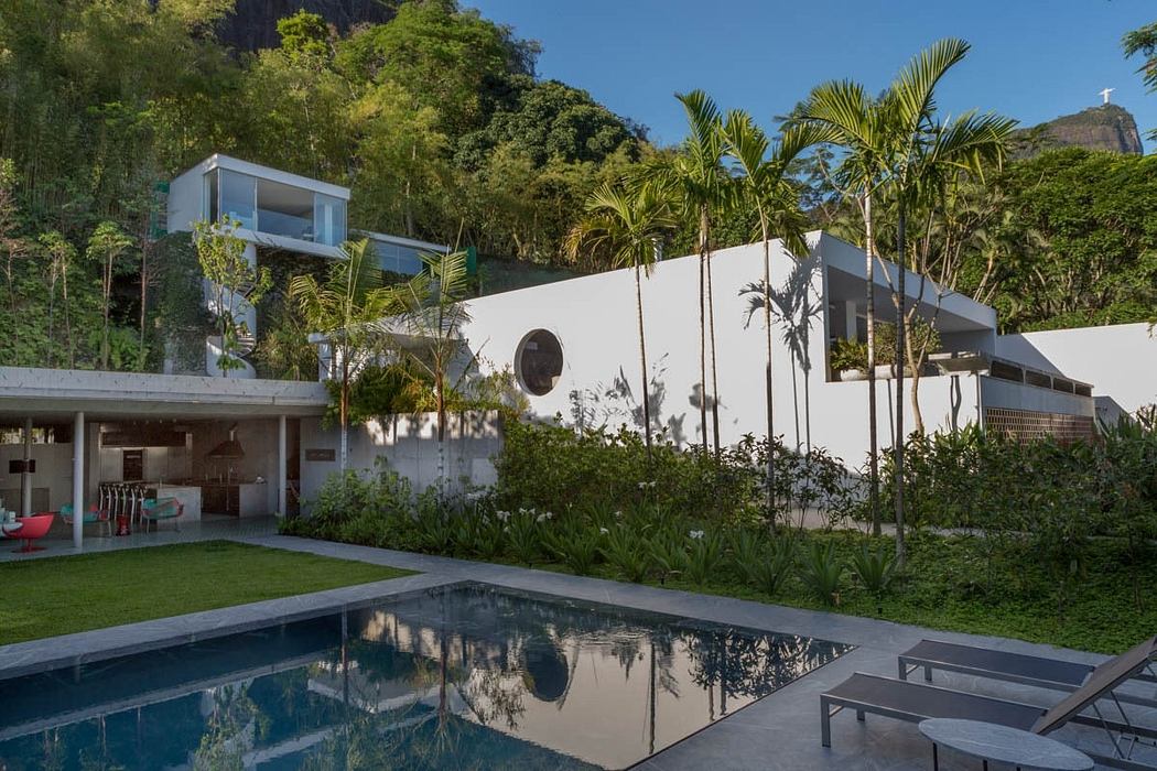 Sleek modern architecture with tropical landscaping and a pool reflecting the surroundings.